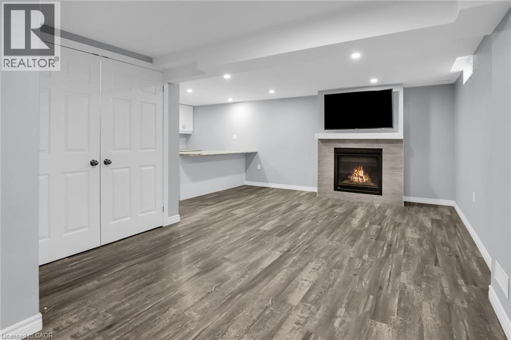 Finished basement with dark wood-type flooring, a fireplace, and recessed lighting - 4432 Dennis Avenue, Beamsville, ON - Indoor With Fireplace