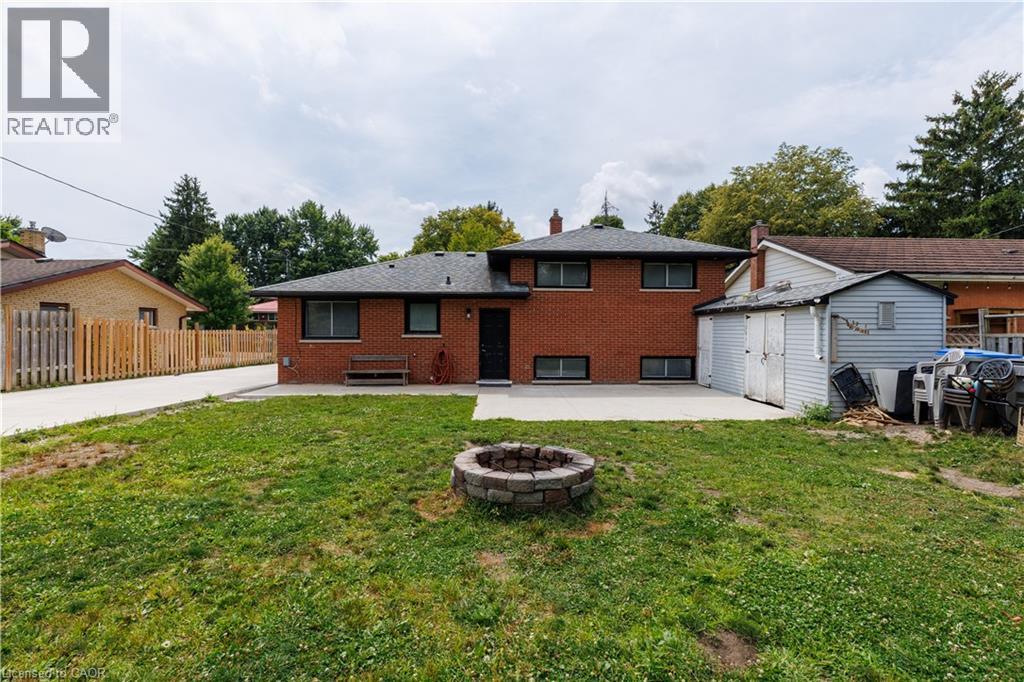 Expansive backyard featuring a stone fire pit, concrete patio, and a detached storage shed - 18 Silverdale Crescent, London, ON - Outdoor