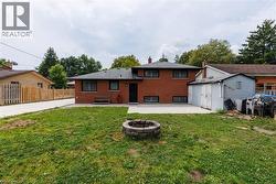 Expansive backyard featuring a stone fire pit, concrete patio, and a detached storage shed -