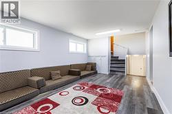 Spacious room featuring wood-finish flooring, light grey walls, and two white-framed windows -