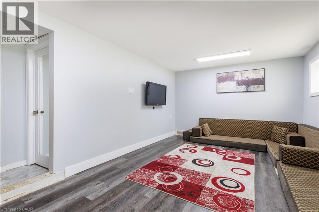 Spacious room featuring wood-finish flooring, light gray walls, and white baseboards - 18 Silverdale Crescent, London, ON - Indoor