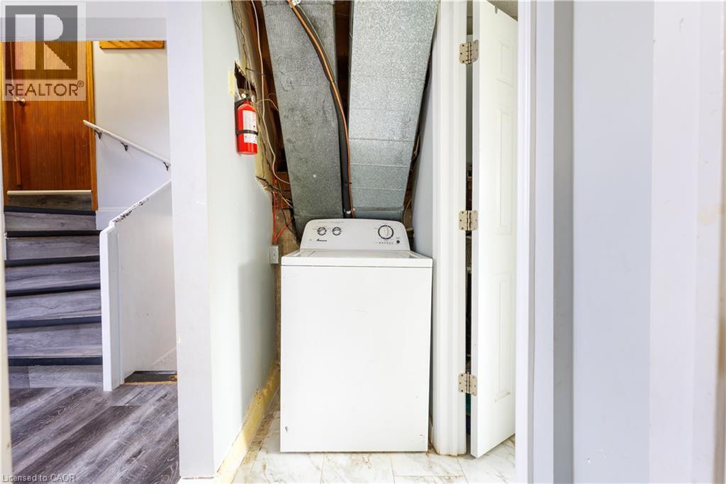 Appliance area featuring a white washing machine, exposed ductwork, and light-colored walls - 18 Silverdale Crescent, London, ON - Indoor Photo Showing Laundry Room