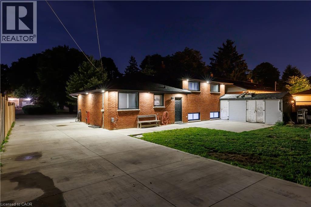 Brick exterior with illuminated wall sconces, a concrete driveway, and a detached storage shed - 18 Silverdale Crescent, London, ON - Outdoor