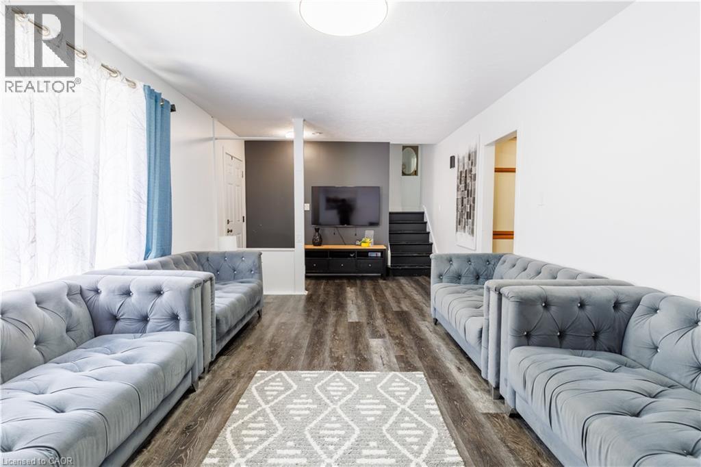 Spacious room featuring wood-finish flooring, a contemporary ceiling light fixture, and white walls - 18 Silverdale Crescent, London, ON - Indoor Photo Showing Living Room