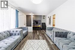 Spacious room featuring wood-finish flooring, a contemporary ceiling light fixture, and white walls -