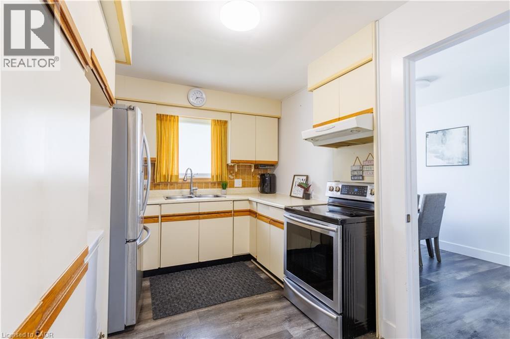 Kitchen featuring a stainless steel refrigerator, electric range, and wood-finish flooring - 18 Silverdale Crescent, London, ON - Indoor Photo Showing Kitchen With Double Sink