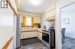 Kitchen featuring a stainless steel refrigerator, electric range, and wood-finish flooring -