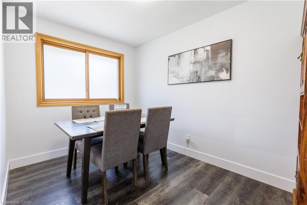 Dining area featuring a wood-frame window, dark wood-finish flooring, white walls, and bright baseboards - 18 Silverdale Crescent, London, ON - Indoor Photo Showing Dining Room