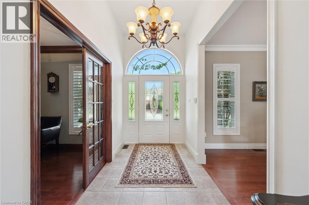 Foyer featuring a grand arched transom window, a chandelier, tile flooring, and a decorative front door with sidelights - 20 Bonniewood Drive, Drayton, ON - Indoor Photo Showing Other Room