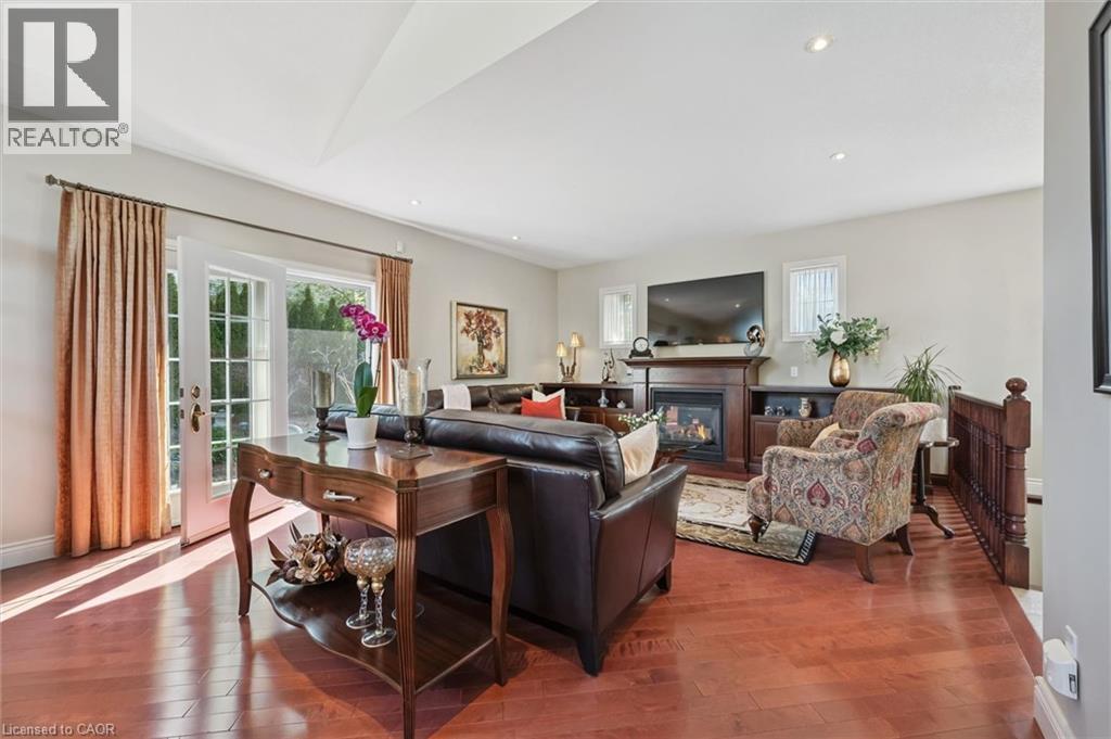 Spacious living area featuring rich wood-finish flooring, a fireplace with a wood mantel, and built-in shelving - 20 Bonniewood Drive, Drayton, ON - Indoor With Fireplace