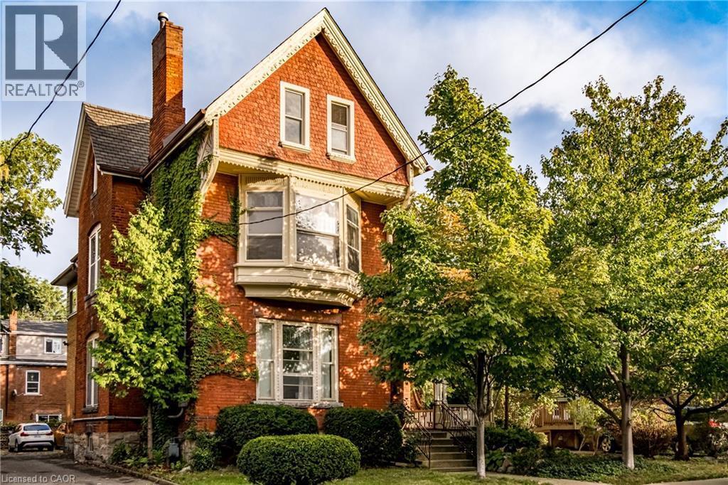 Red brick residence featuring a prominent bay window, white window trim, and a gabled roofline - 95-97 S Fairholt Road S, Hamilton, ON - Outdoor