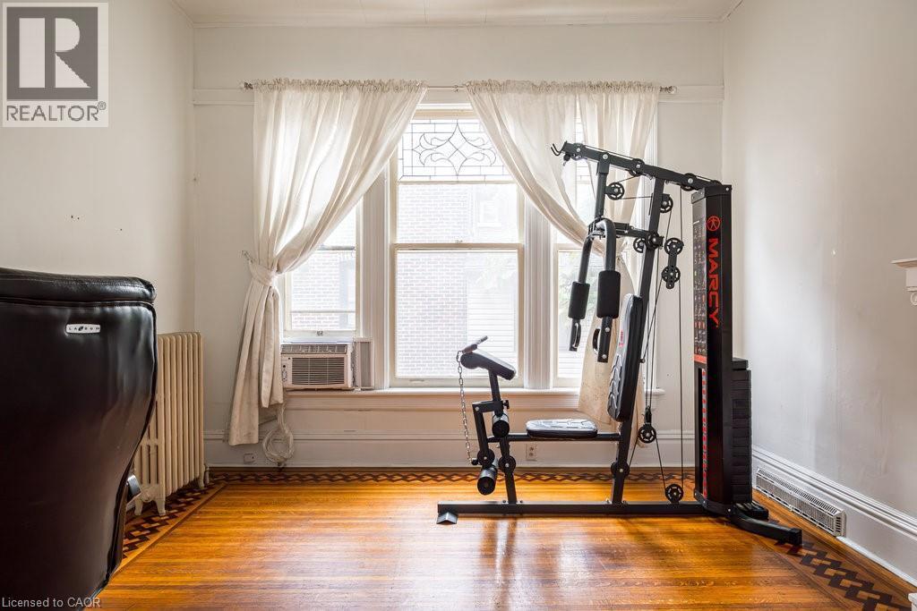 Hardwood flooring with decorative border, complemented by white baseboards and window trim - 95-97 S Fairholt Road S, Hamilton, ON - Indoor Photo Showing Gym Room