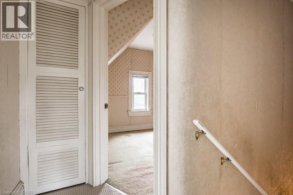 Interior room featuring a single window, sloped ceiling, and textured wallpaper - 95-97 S Fairholt Road S, Hamilton, ON - Indoor Photo Showing Other Room