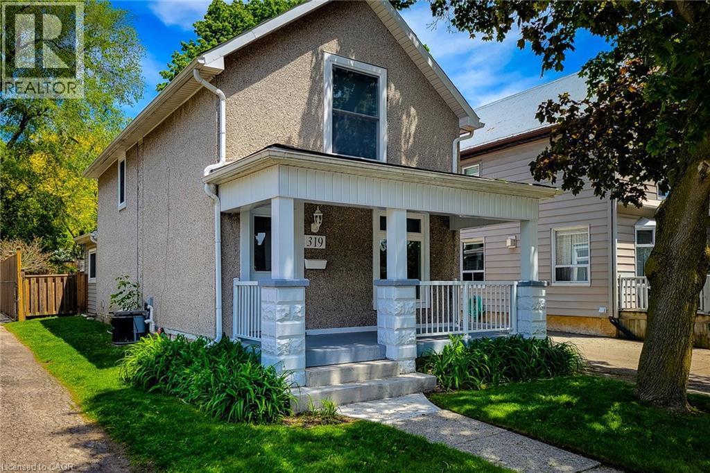 Stucco exterior featuring a covered front porch with white columns and stone accents - 319 King Street W, Dundas, ON - Outdoor