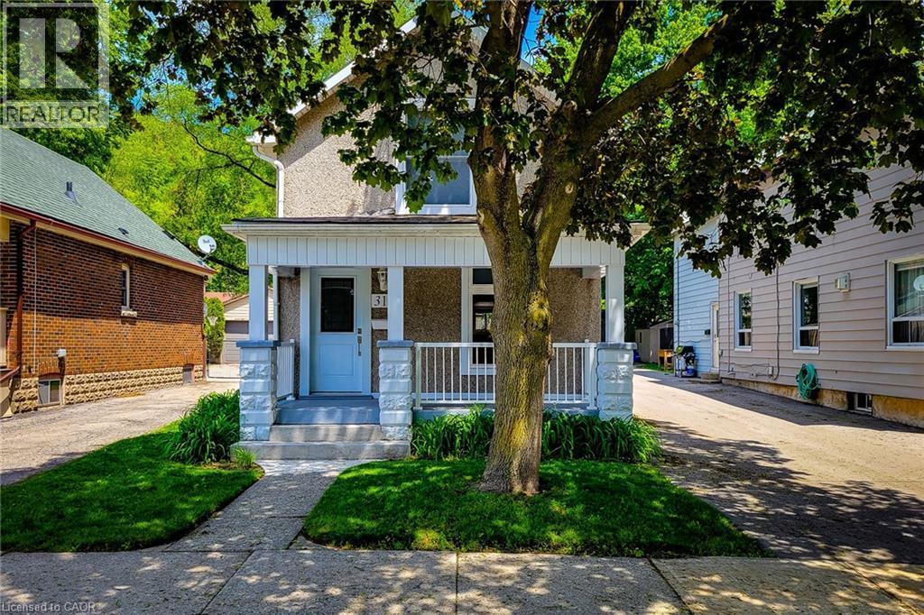 Front facade featuring a covered porch with white columns and railings, a light blue entry door, and a stucco finish on the upper level - 319 King Street W, Dundas, ON - Outdoor With Deck Patio Veranda