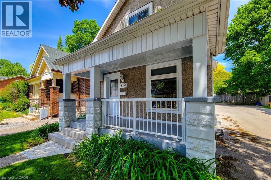 Inviting front porch featuring a white railing and stone-clad pillars - 319 King Street W, Dundas, ON - Outdoor With Deck Patio Veranda