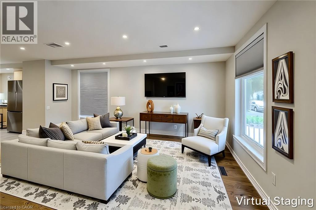 Open-concept living area featuring rich wood-finish flooring, recessed lighting, and ample natural light from multiple windows - 319 King Street W, Dundas, ON - Indoor Photo Showing Living Room
