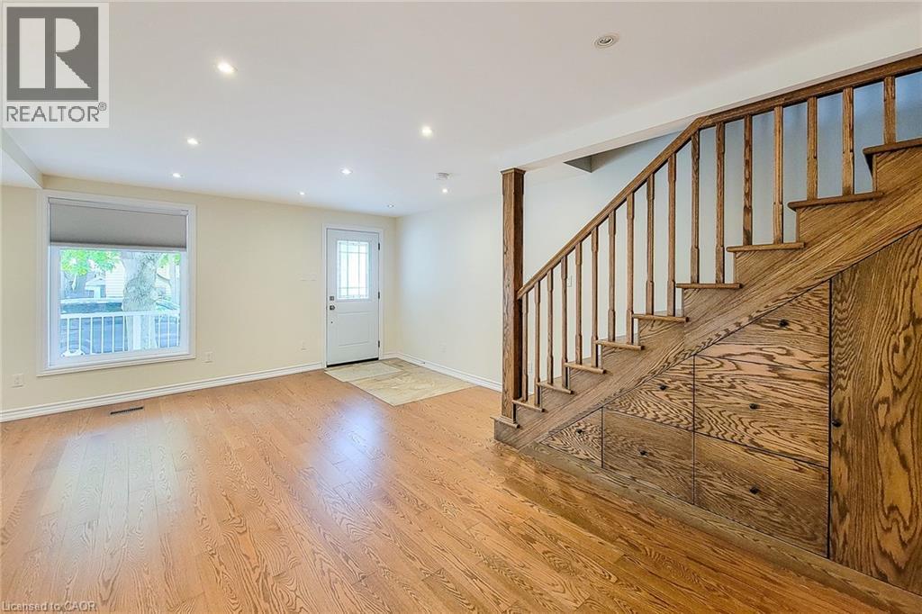 Hardwood flooring and recessed lighting illuminate this room, featuring a staircase with integrated storage - 319 King Street W, Dundas, ON - Indoor Photo Showing Other Room