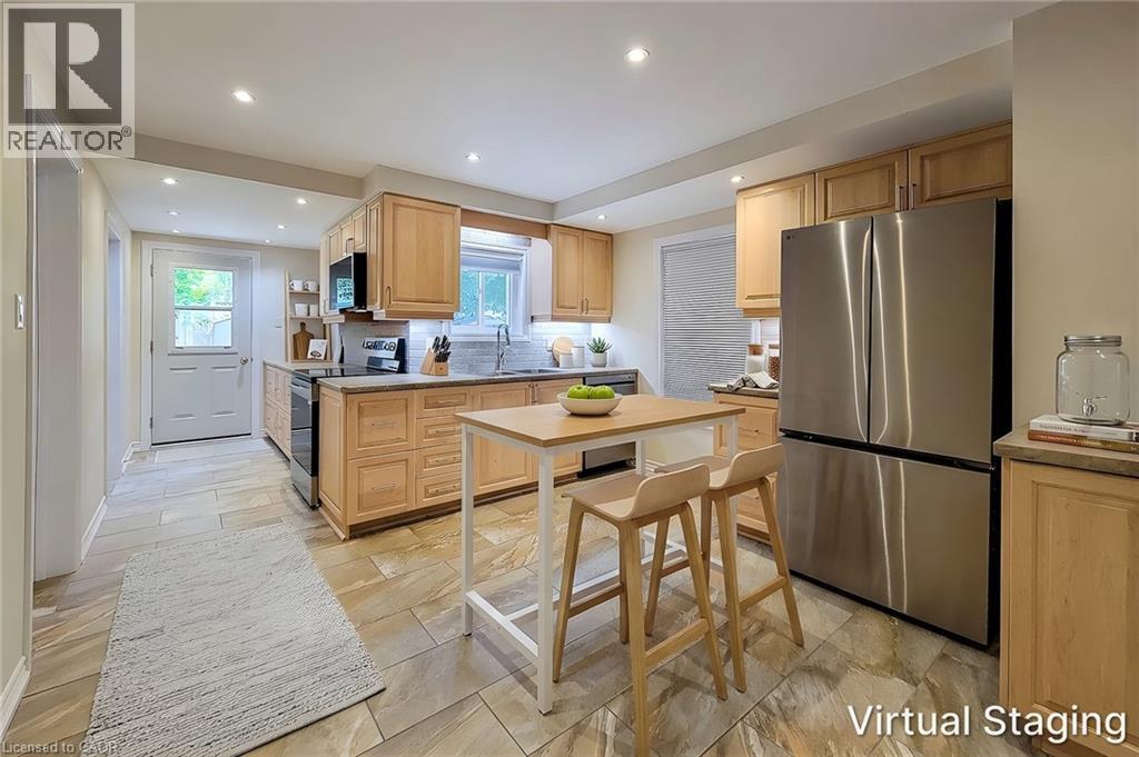 Kitchen featuring natural wood-finish cabinetry, stainless steel appliances, stone-look tile flooring, recessed lighting, and a rear exterior door - 319 King Street W, Dundas, ON - Indoor Photo Showing Kitchen