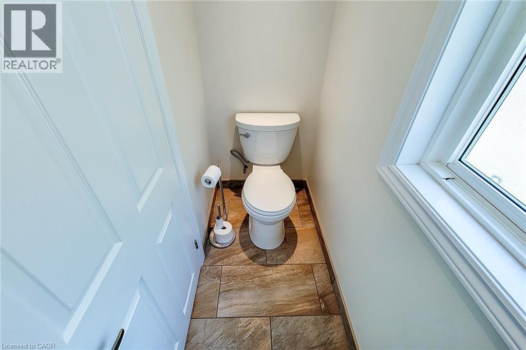 White toilet featuring a standard bowl, tank, and base - 319 King Street W, Dundas, ON - Indoor Photo Showing Bathroom