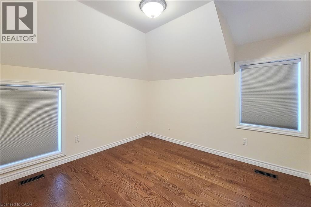 Room featuring wood-finish flooring, two windows with blinds, and white trim - 319 King Street W, Dundas, ON - Indoor Photo Showing Other Room