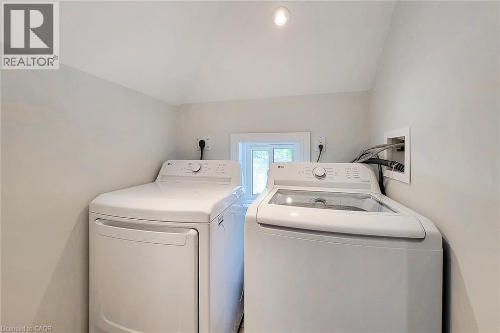 Dedicated laundry area with a white top-load washing machine and a white front-load dryer - 319 King Street W, Dundas, ON - Indoor Photo Showing Laundry Room
