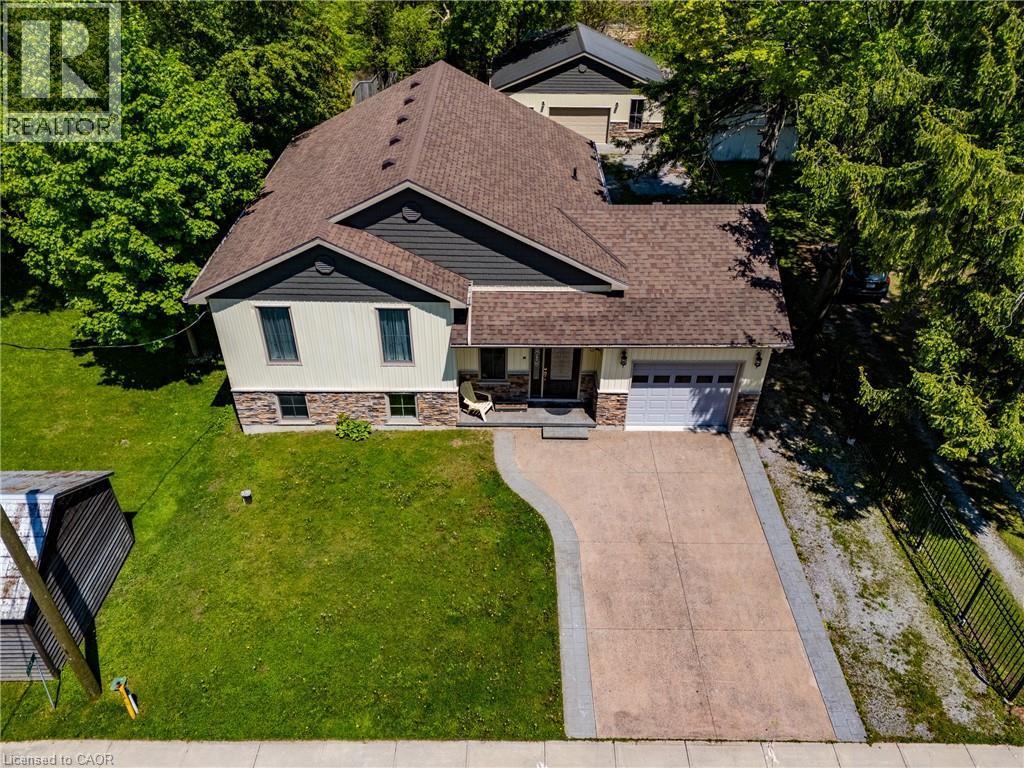 Contemporary residence featuring a combination of siding and stone veneer, an attached garage, a concrete driveway, and mature landscaping with established trees - 514 Fishers Glen Road, Vittoria, ON - Outdoor