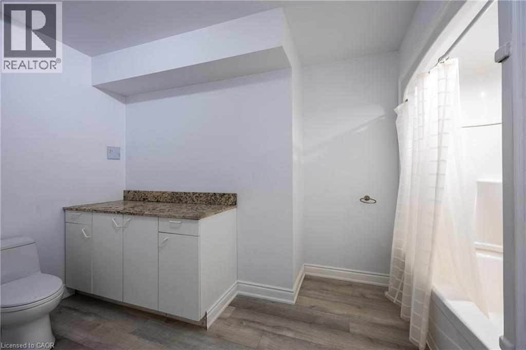 Full bathroom featuring a white toilet, a shower-over-tub combination, and a vanity with a stone-finish countertop - 514 Fishers Glen Road, Vittoria, ON - Indoor Photo Showing Bathroom