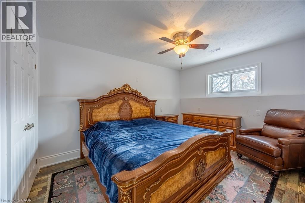 Bedroom featuring wood-finish flooring, a white paneled door, and a white-framed window - 514 Fishers Glen Road, Vittoria, ON - Indoor Photo Showing Bedroom