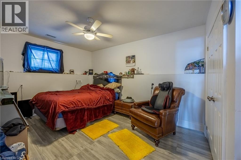 Room featuring wood-finish flooring, a ceiling fan with integrated lighting, and a white paneled door - 514 Fishers Glen Road, Vittoria, ON - Indoor Photo Showing Bedroom