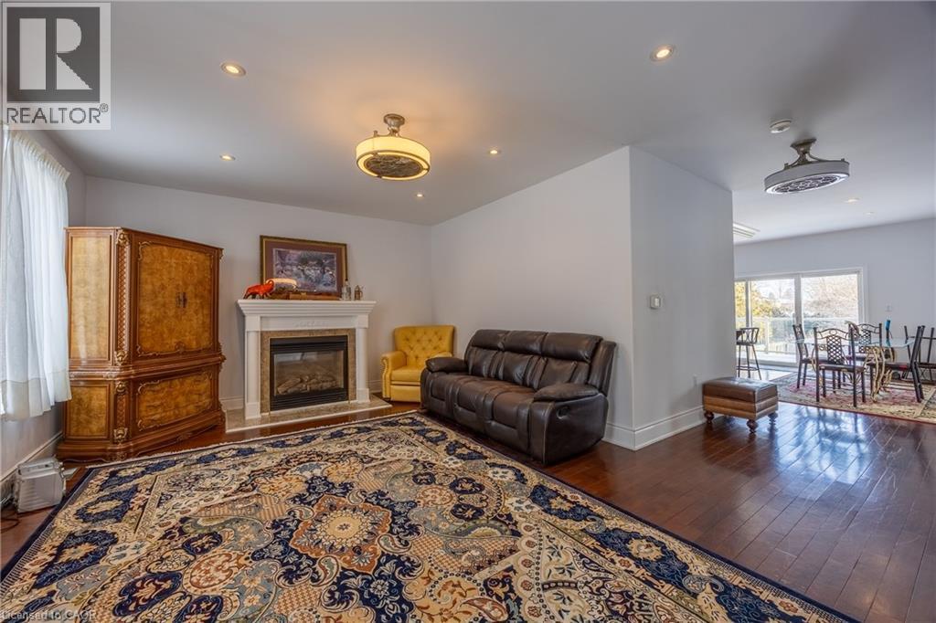 Living area featuring wood-finish flooring, a built-in fireplace with a stone surround, recessed lighting, and a ceiling fan - 514 Fishers Glen Road, Vittoria, ON - Indoor Photo Showing Living Room With Fireplace