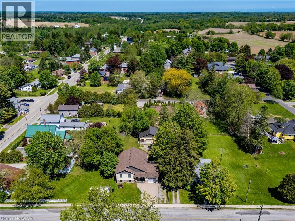 Aerial perspective highlighting a residential property with a light-colored exterior and brown shingle roof, positioned amidst extensive green landscaping and mature trees - 514 Fishers Glen Road, Vittoria, ON - Outdoor With View