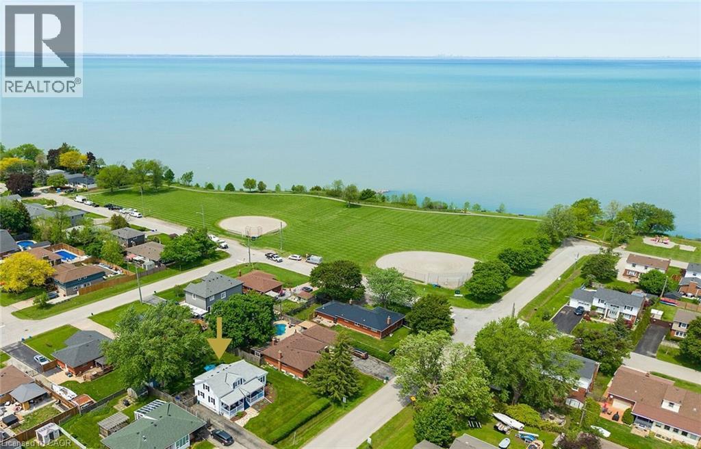 Property featuring a white-sided exterior, mature trees, and a spacious green lawn - 439 Murray Street, Grimsby, ON - Outdoor With Body Of Water With View