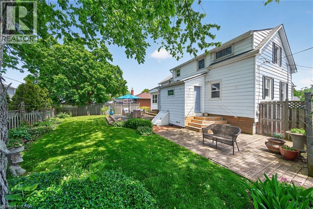 Expansive rear yard featuring a wooden deck, a brick patio, and mature trees - 439 Murray Street, Grimsby, ON - Outdoor