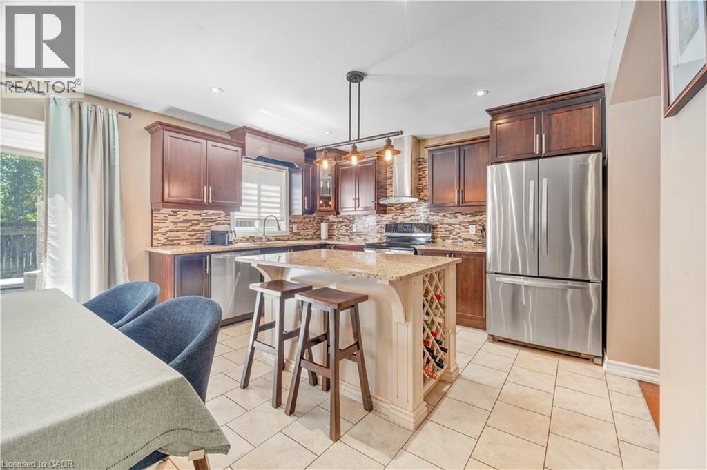 Kitchen featuring dark wood cabinetry, stainless steel appliances, a tile backsplash, and a central island with integrated wine storage - 21 Davinci Boulevard, Hamilton, ON - Indoor Photo Showing Kitchen With Stainless Steel Kitchen With Upgraded Kitchen