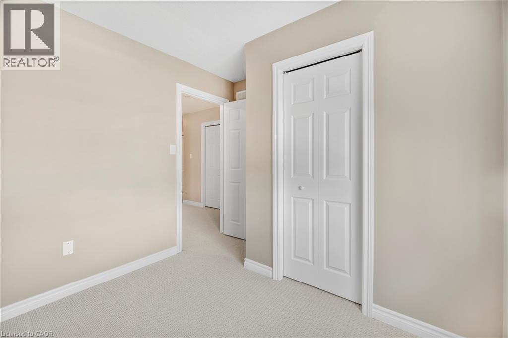 Hallway featuring light beige wall paint, white trim, light-colored carpet, and multiple six-panel bifold doors - 21 Davinci Boulevard, Hamilton, ON - Indoor Photo Showing Other Room