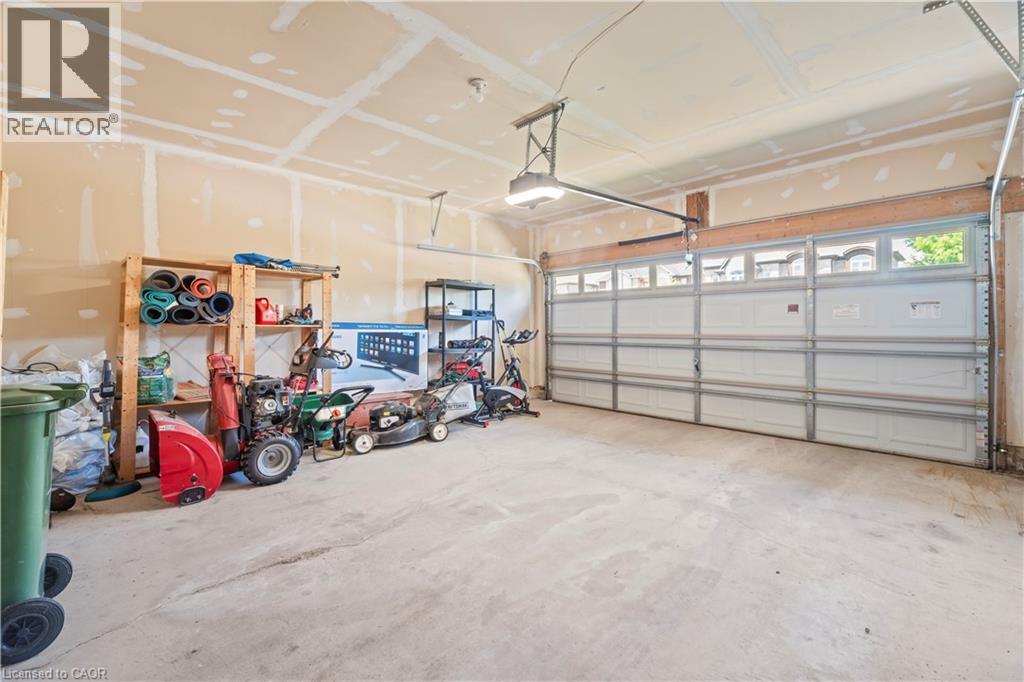 Spacious garage featuring a concrete floor, overhead lighting, and a white paneled garage door with upper window inserts - 21 Davinci Boulevard, Hamilton, ON - Indoor Photo Showing Garage