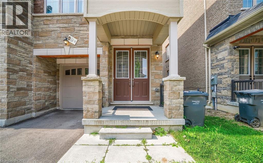 Stone facade featuring a covered porch with stone pillars, dual entry doors with glass inserts, and an attached garage with a panel door - 14 Faye Street, Brampton, ON - Outdoor