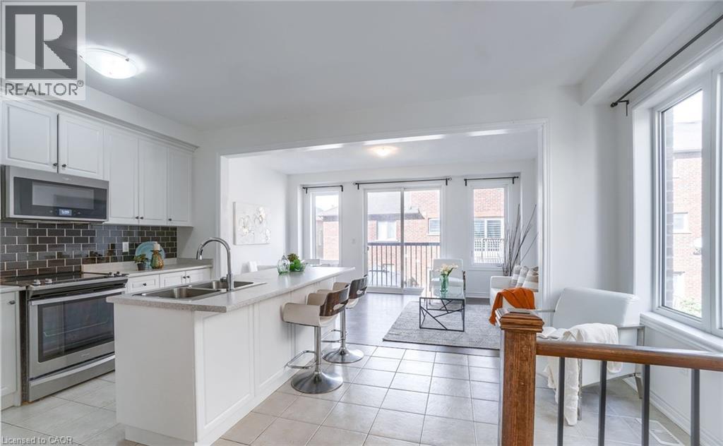 Bright kitchen featuring white cabinetry, stainless steel appliances, a subway tile backsplash, and an island with bar seating - 14 Faye Street, Brampton, ON - Indoor Photo Showing Kitchen With Double Sink With Upgraded Kitchen
