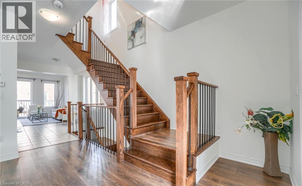 Hardwood staircase with wrought iron balusters and wood newel posts, complementing the wood-finish flooring - 14 Faye Street, Brampton, ON - Indoor Photo Showing Other Room