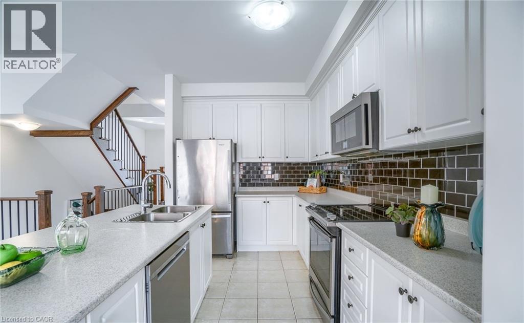 Bright kitchen featuring white cabinetry, stainless steel appliances, a subway tile backsplash, and light-toned countertops - 14 Faye Street, Brampton, ON - Indoor Photo Showing Kitchen With Stainless Steel Kitchen With Double Sink With Upgraded Kitchen
