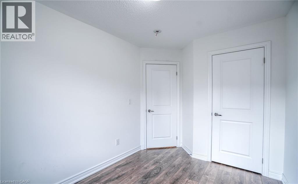 Interior room featuring wood-finish flooring, white baseboards, and two solid panel doors with chrome hardware - 14 Faye Street, Brampton, ON - Indoor Photo Showing Other Room