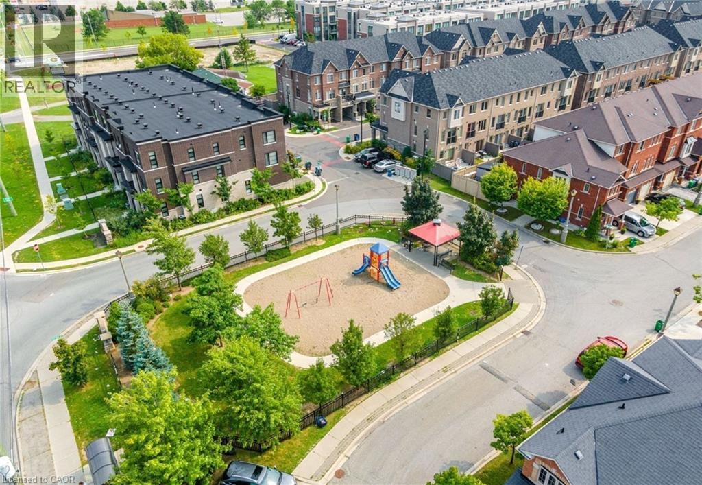 Community green space featuring a sandbox play area with a slide and swings, surrounded by mature trees and paved walkways - 14 Faye Street, Brampton, ON - Outdoor With View