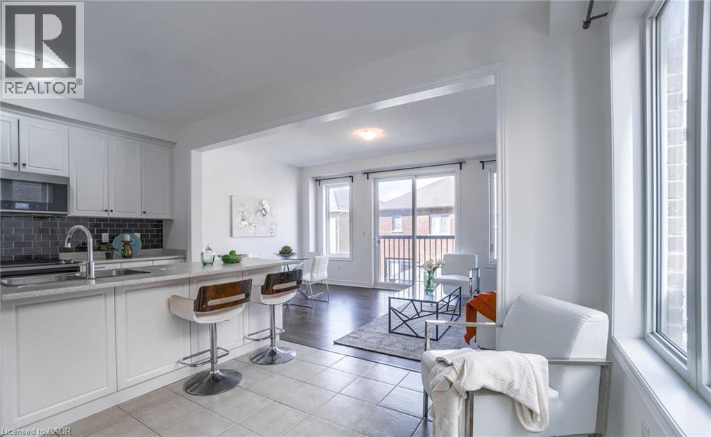 Kitchen featuring white cabinetry, stainless steel appliances, a dark tile backsplash, and a breakfast bar with seating - 14 Faye Street, Brampton, ON - Indoor Photo Showing Kitchen
