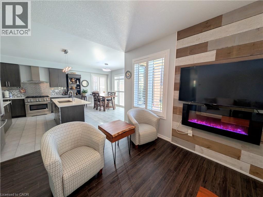 Open-concept living area featuring rich wood-finish flooring and a fireplace with a multi-tone wood-paneled accent wall - 37 Mull Avenue, Caledonia, ON - Indoor