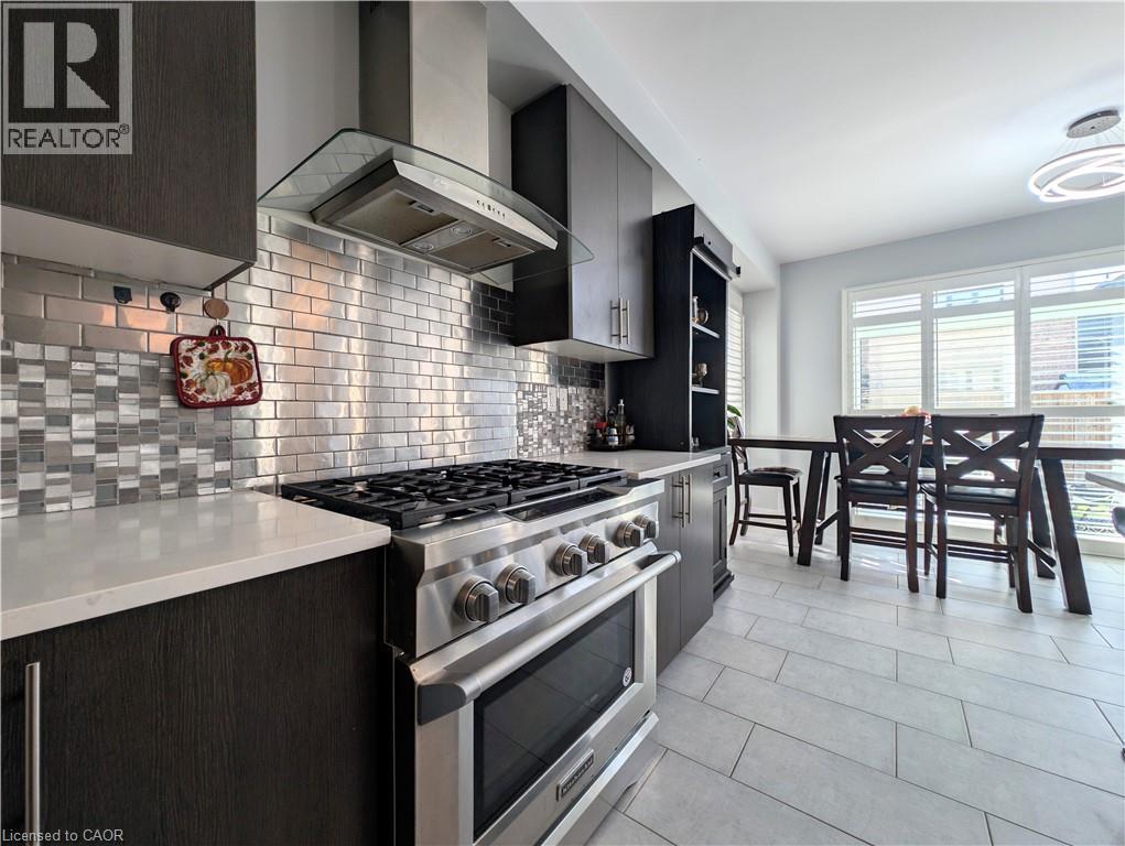 Modern kitchen featuring stainless steel appliances, dark wood-finish cabinetry, and light-toned countertops - 37 Mull Avenue, Caledonia, ON - Indoor Photo Showing Kitchen With Upgraded Kitchen