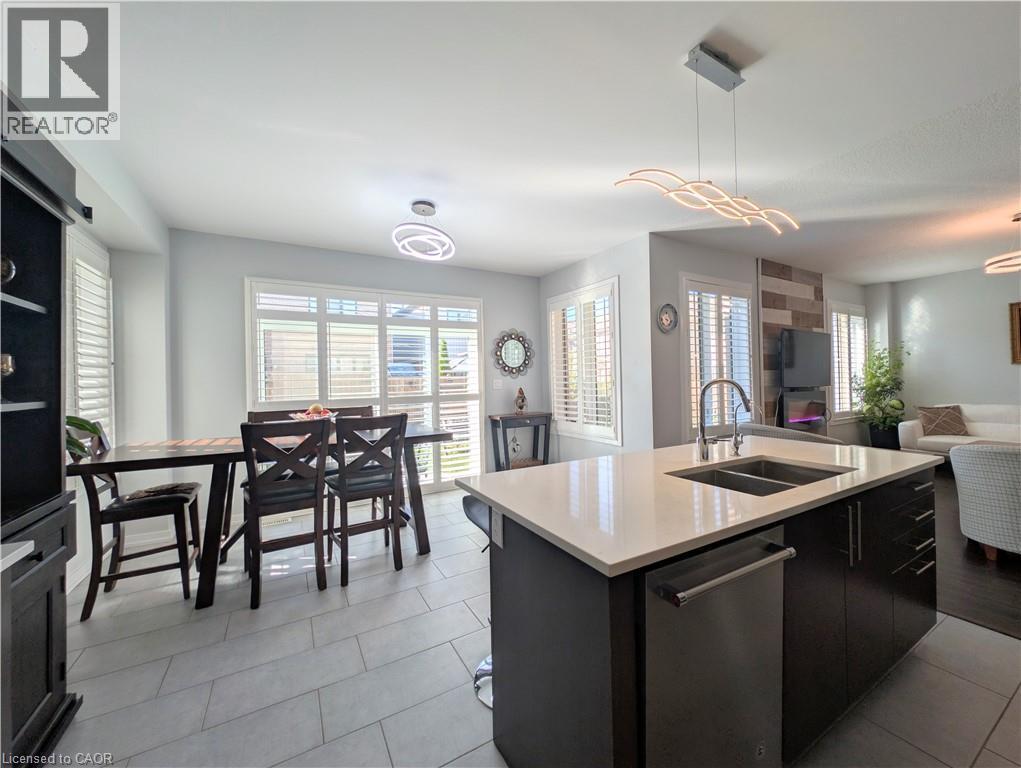Open-concept kitchen featuring a center island with sink and stainless steel dishwasher, quartz countertops, and modern pendant lighting - 37 Mull Avenue, Caledonia, ON - Indoor