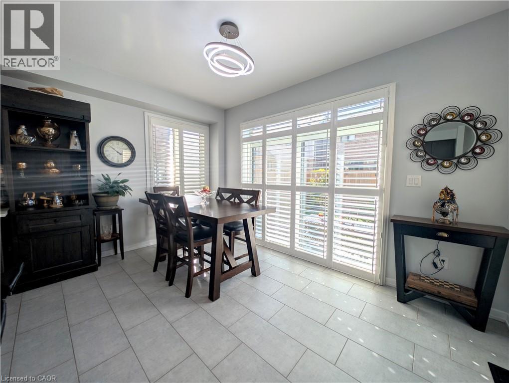 Dining area featuring light-toned tile flooring, white plantation shutters, and a modern circular ceiling light fixture - 37 Mull Avenue, Caledonia, ON - Indoor Photo Showing Dining Room
