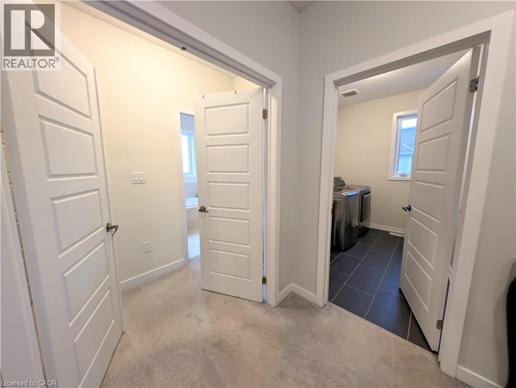 Hallway with light gray carpeting, white trim, and white paneled doors - 37 Mull Avenue, Caledonia, ON - Indoor Photo Showing Other Room