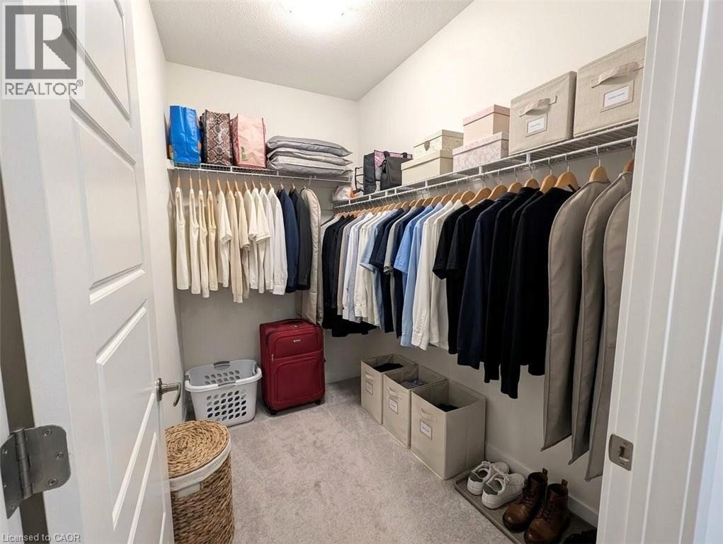 Walk-in closet featuring light grey carpeting, white wire shelving, and extensive hanging rods - 37 Mull Avenue, Caledonia, ON - Indoor With Storage